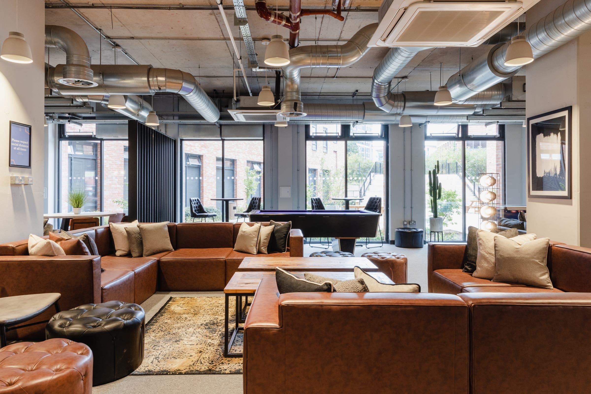 Residents' lounge at Globe Works with leather sofas and doors onto the courtyard
