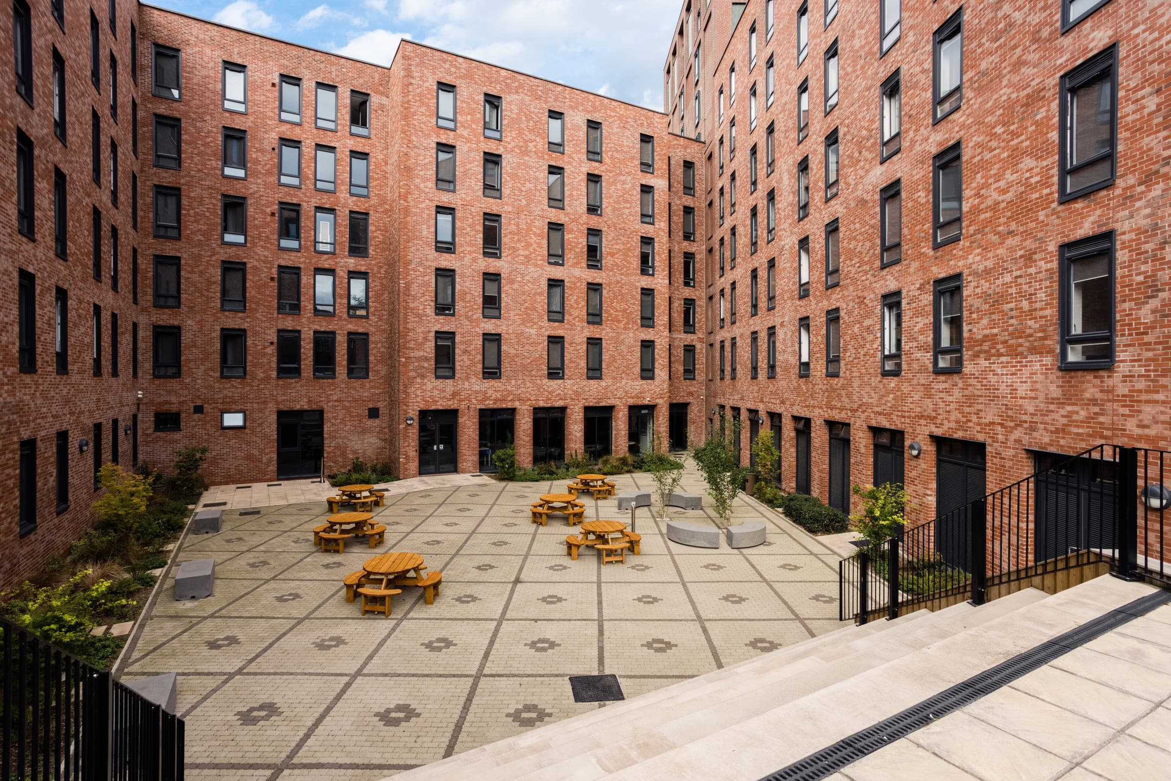 The courtyard at Globe Works from above, enclosed by brick on all sides, with picnic benches across the paving