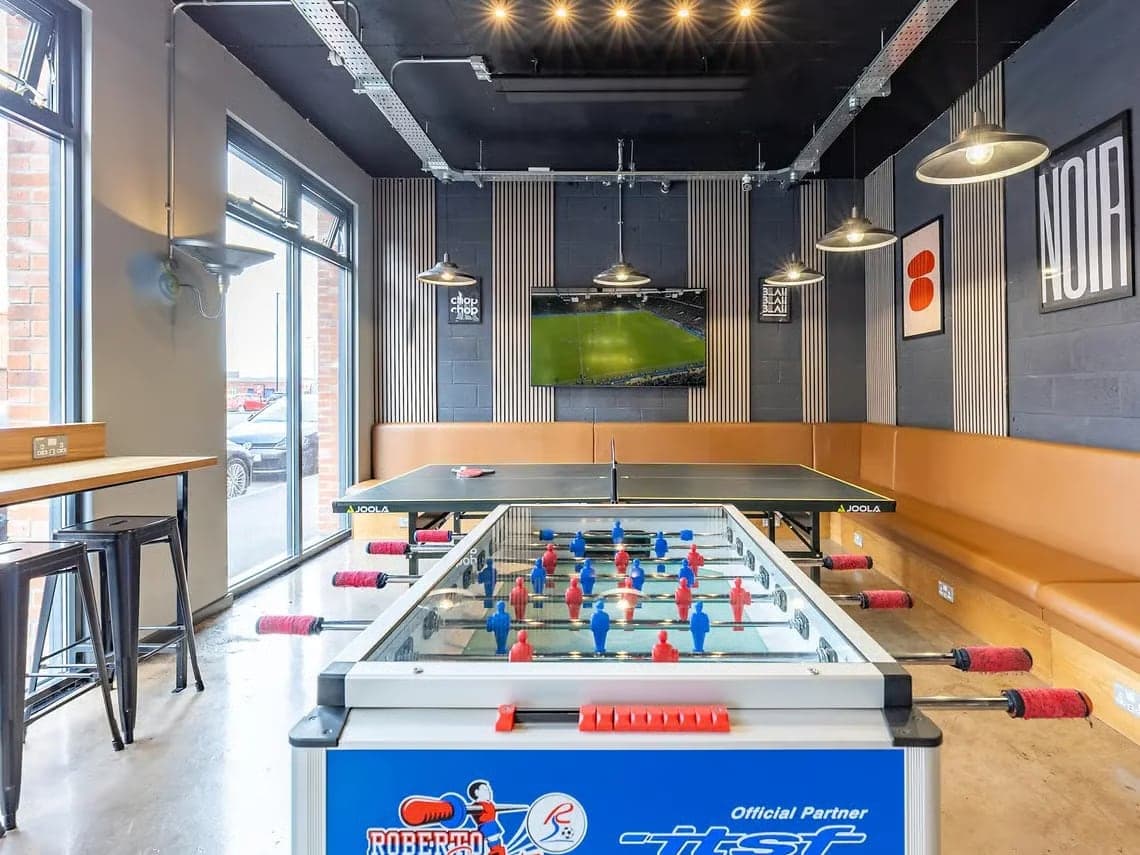 Table football and table tennis in the games room at Globe Works, with banquette seating and a big screen