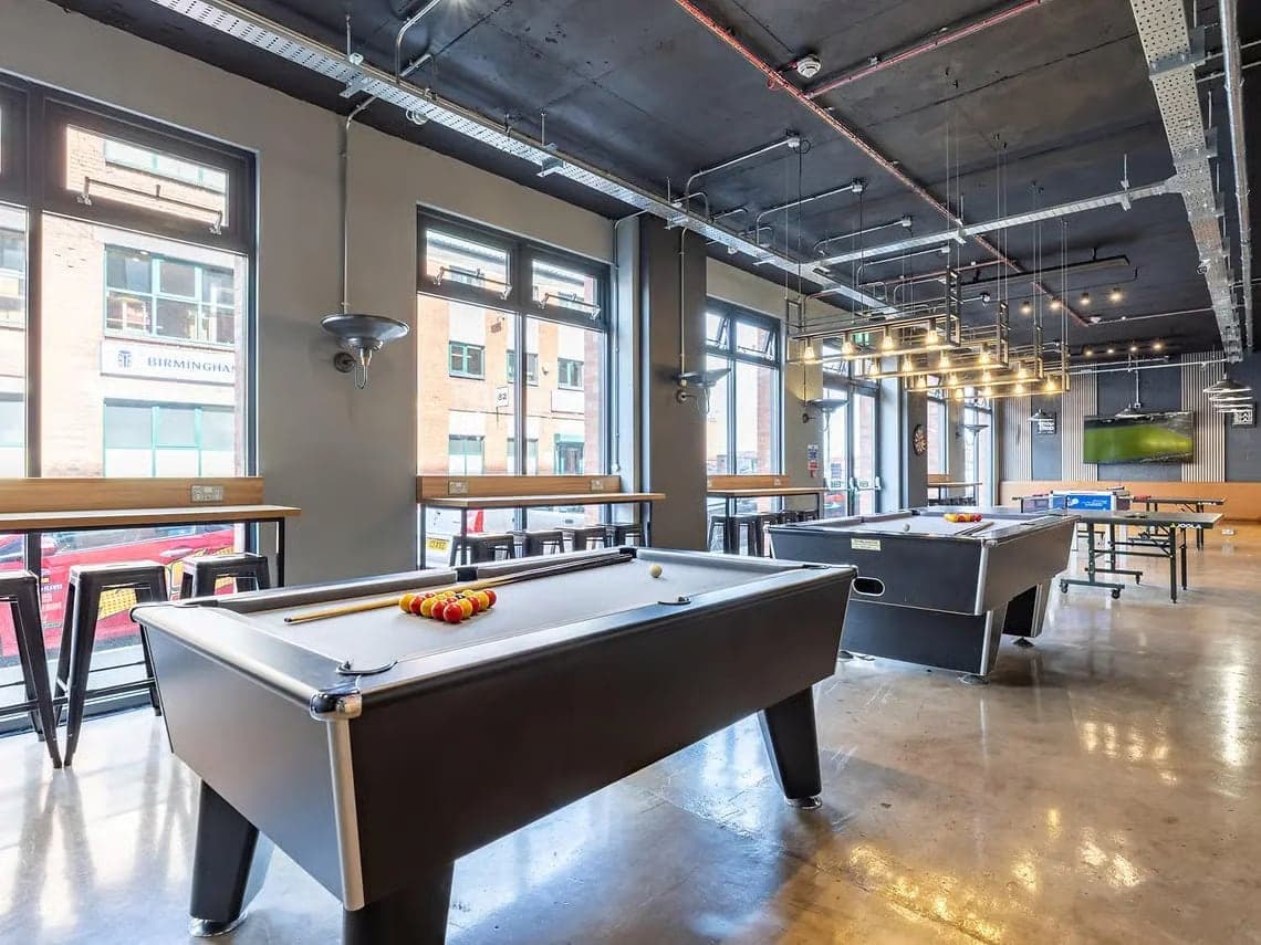 Pool tables in the games room at Globe Works, with tall windows onto the street