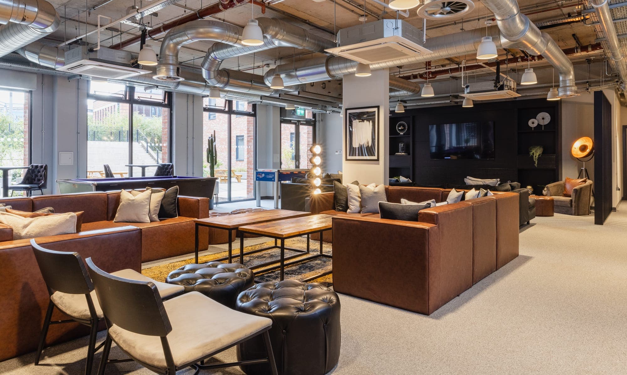 Seating in the communal lounge at Globe Works, with a pool table and the courtyard beyond