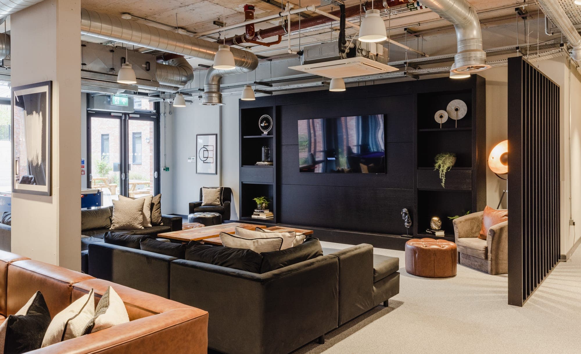 Communal lounge at Globe Works with a large wall-mounted television and armchairs