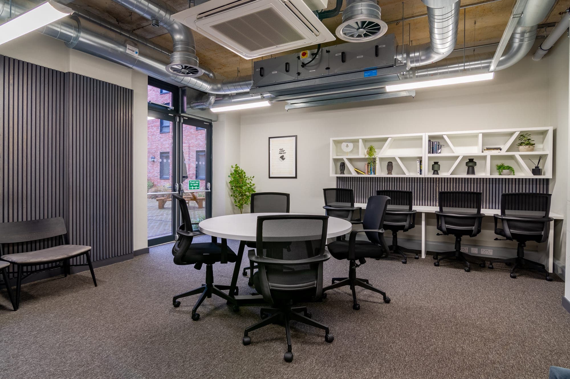 The meeting room at Globe Works with a round table and desks along the wall