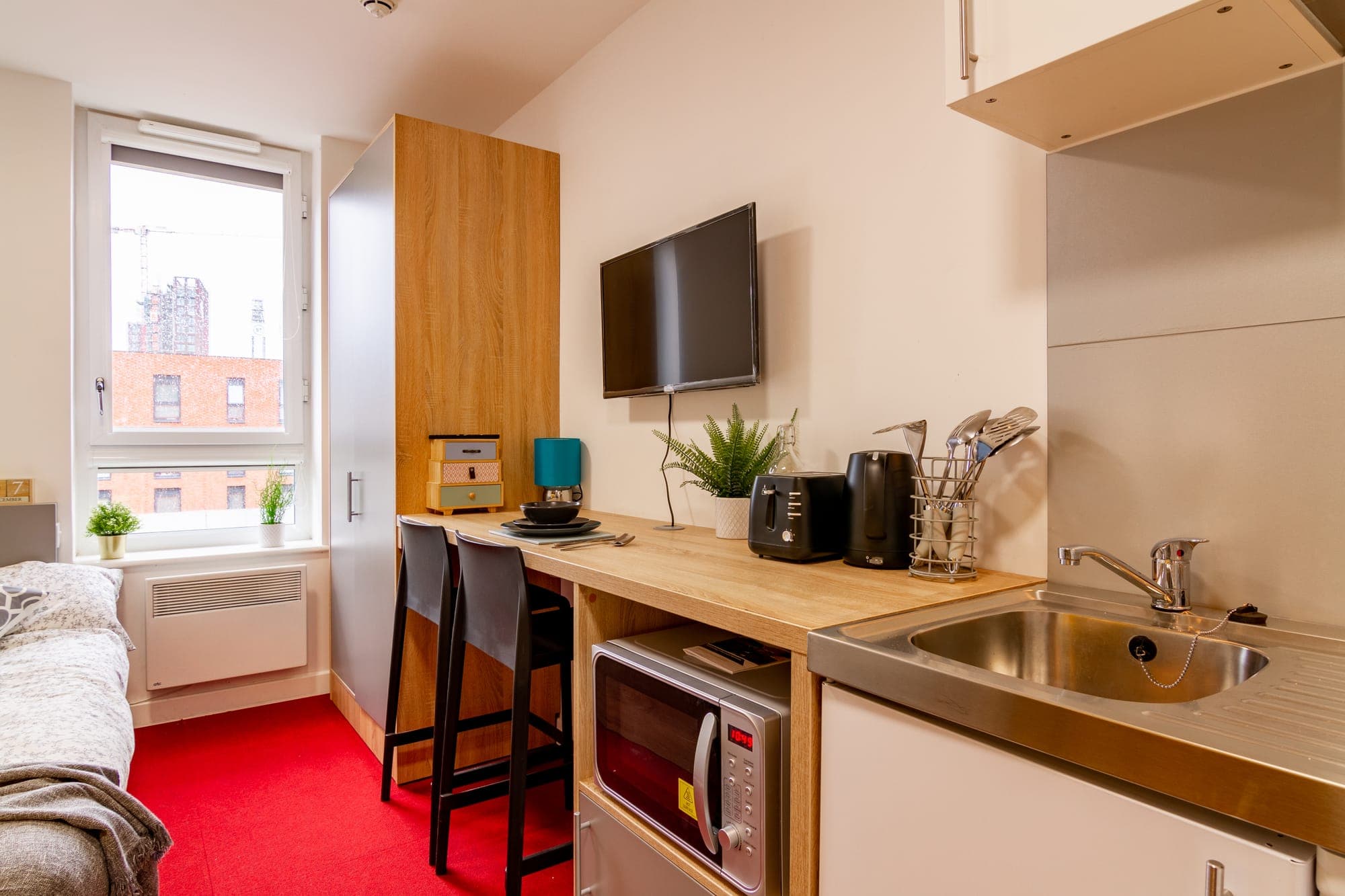 A standard studio at Globe Works with a private kitchenette, breakfast bar and wall-mounted TV