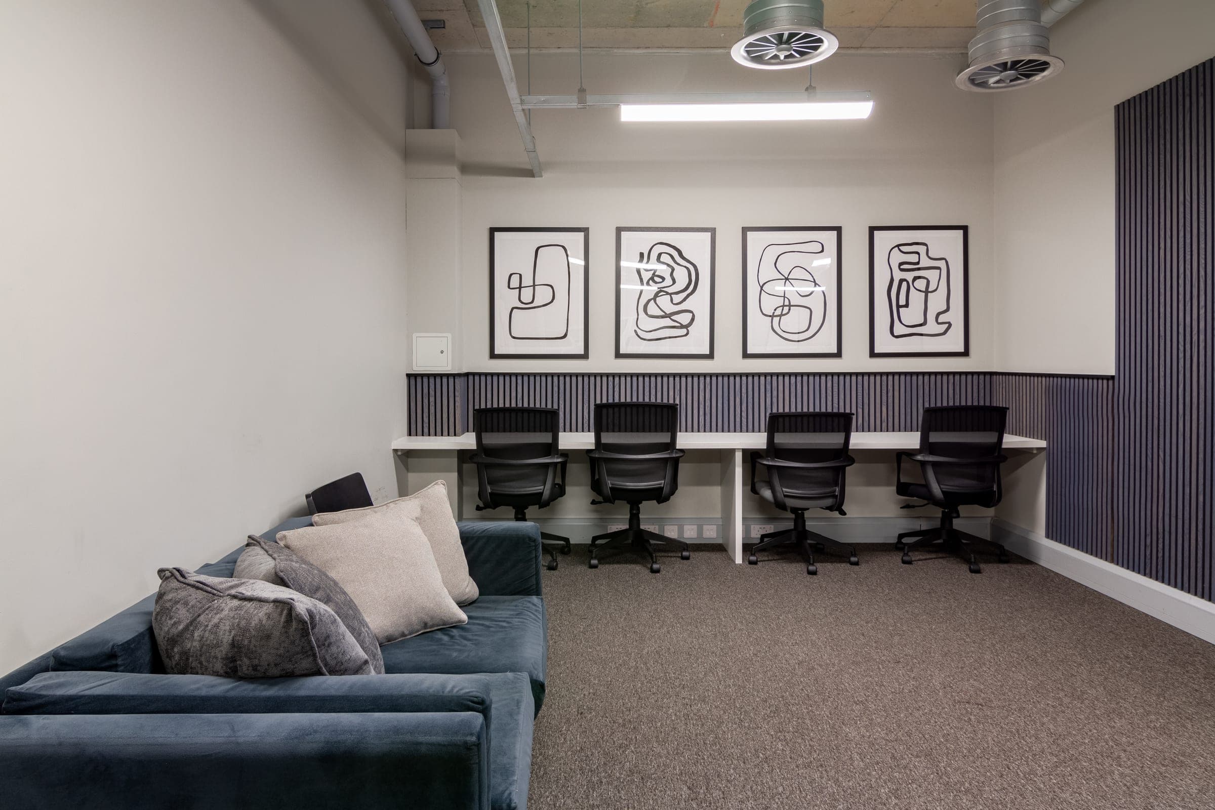 Study room at Globe Works with a run of desks, task chairs and a velvet sofa