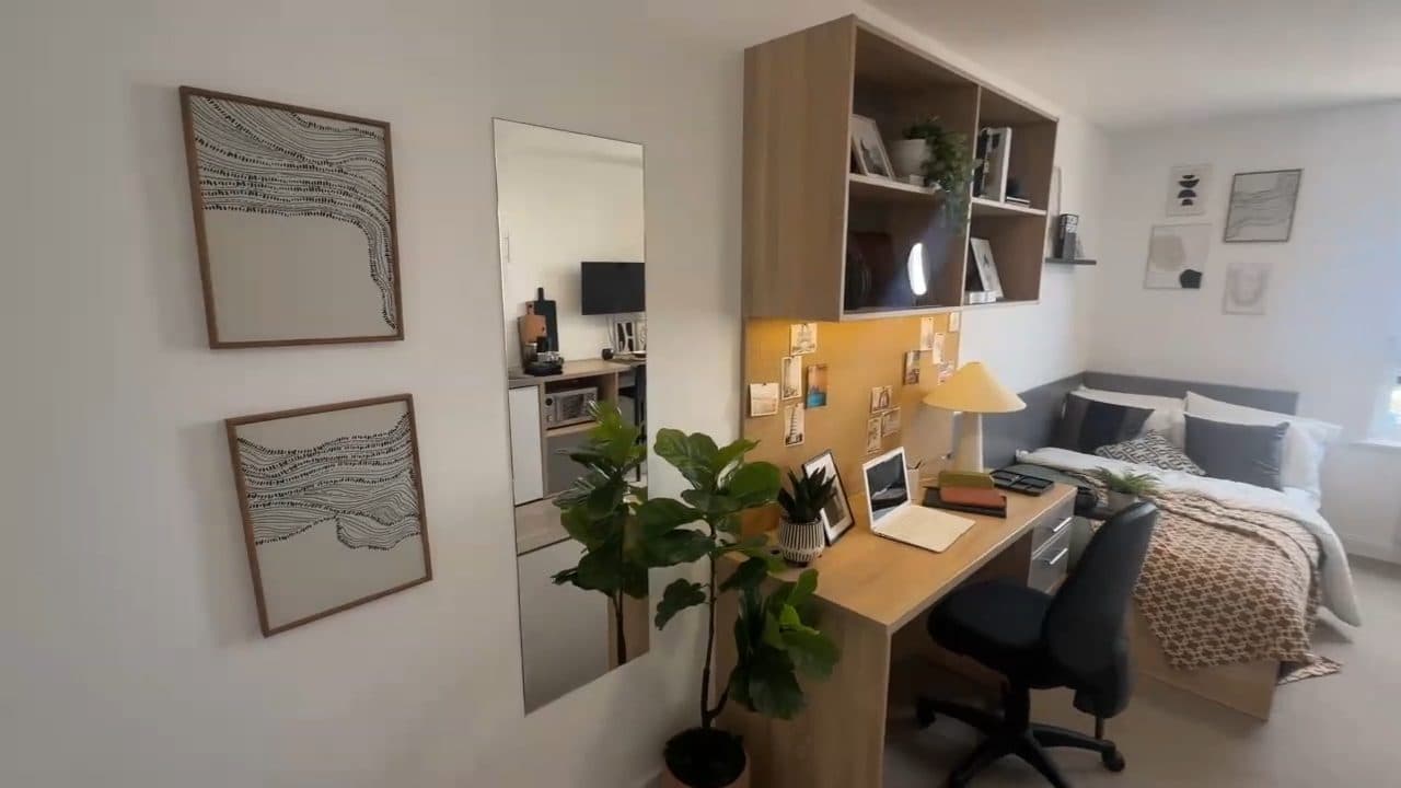 A studio at Globe Works with a double bed, a study desk and its own kitchen along one wall